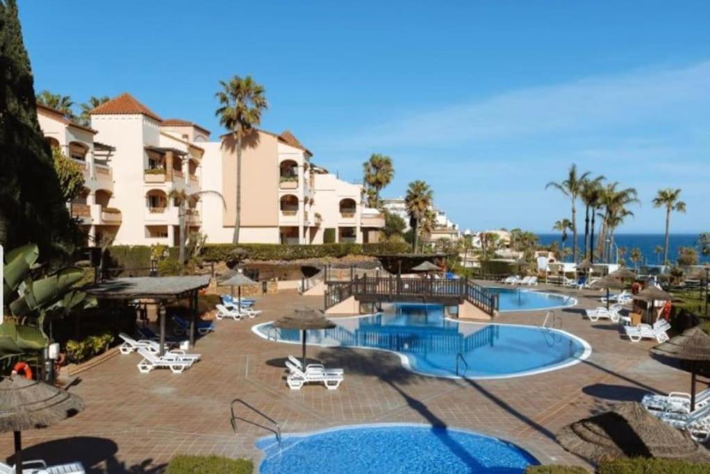 un complejo con 2 piscinas, sillas y sombrillas en marina del sol 232, en Málaga