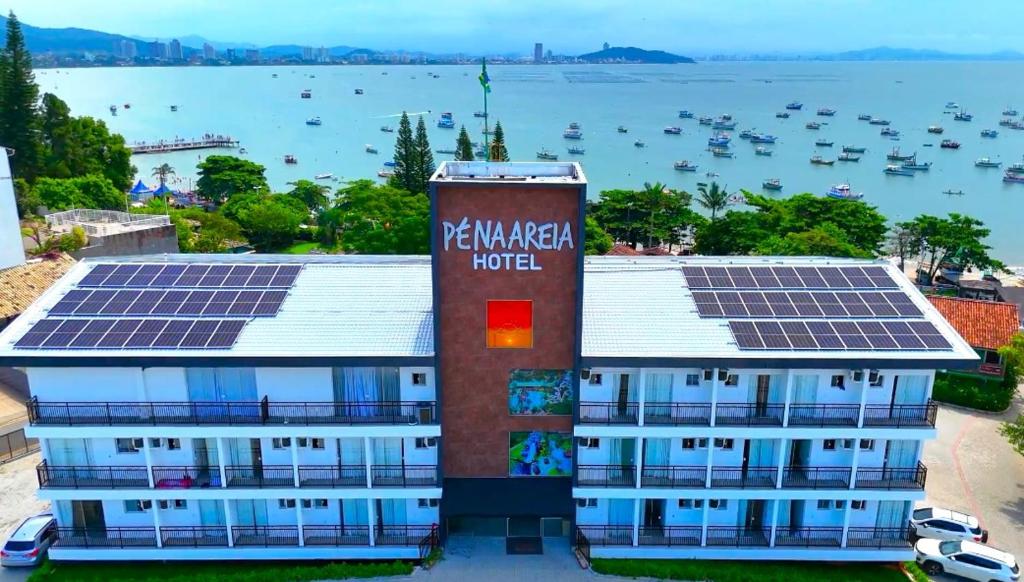 a building with solar panels on the roof with a harbor at Hotel Pé na Areia in Penha
