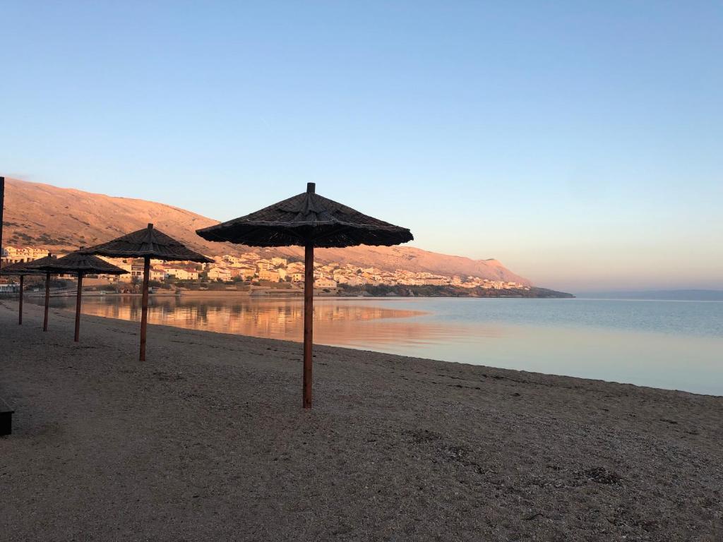 a row of umbrellas on a beach near the water at Villa Melissa in Pag