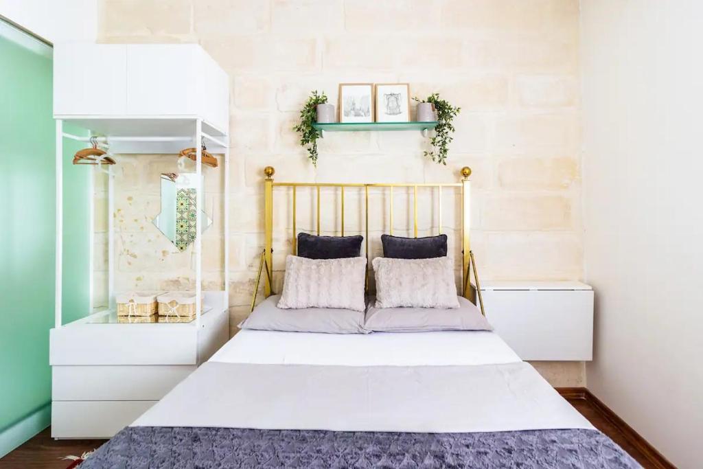 a bedroom with a bed with white sheets and pillows at Gallo House in Cospicua