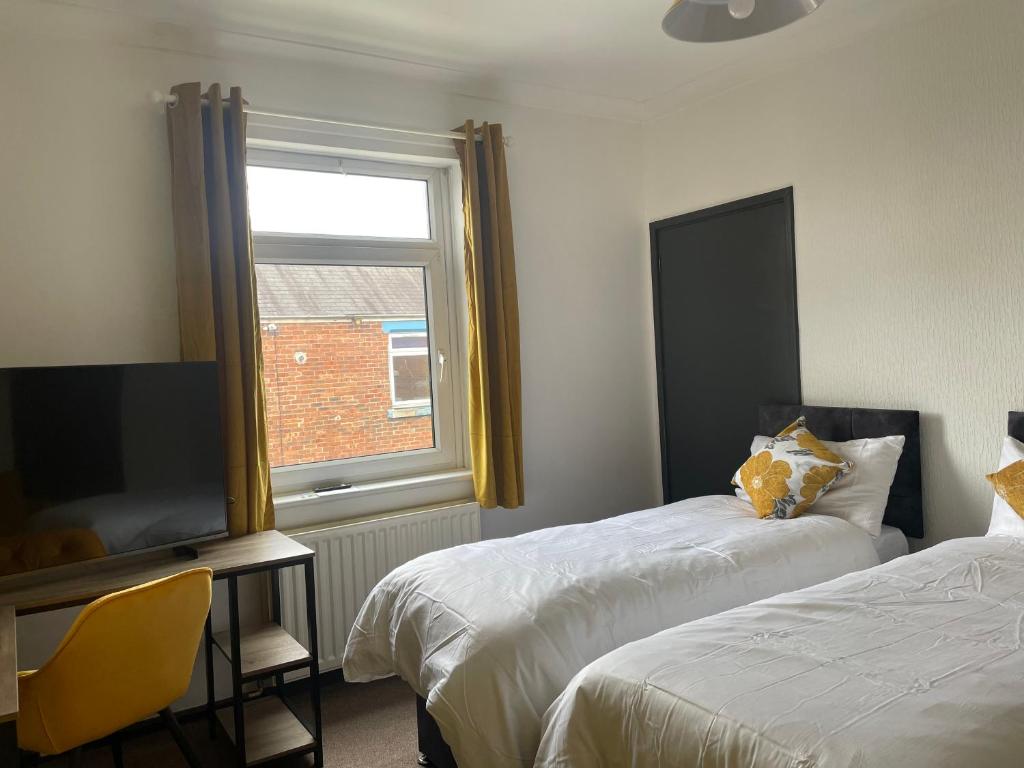 a bedroom with two beds and a tv and a window at Quirky and Cosy Two Bed in Ferryhill Near Durham! - Available as individual rooms or the Entire Property! in Ferryhill