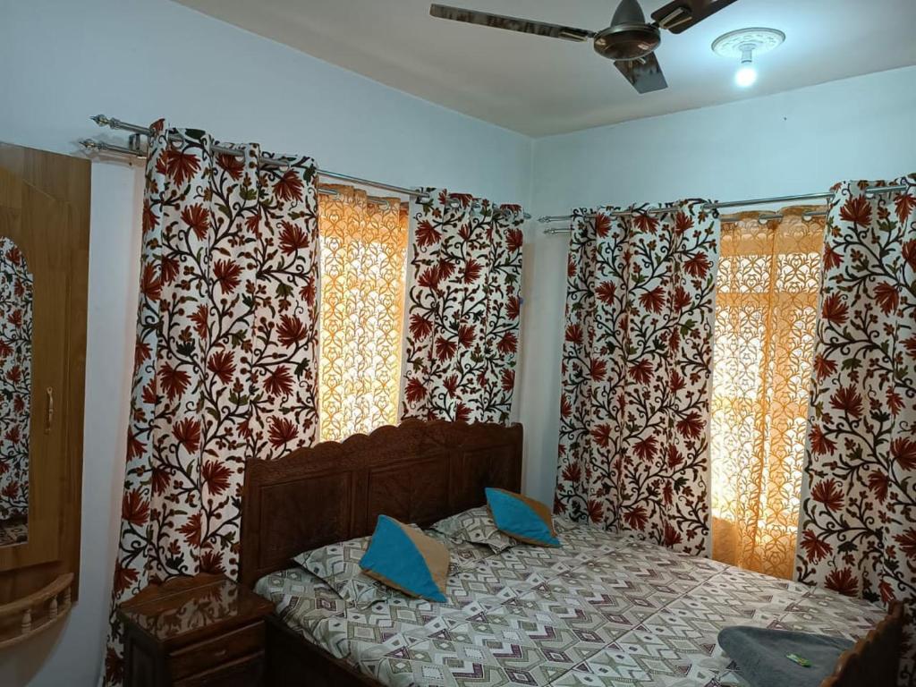 Schlafzimmer mit einem Bett und einem Fenster mit Vorhängen in der Unterkunft The Hotel "Shafeeq" Across jawahar bridge in Srinagar