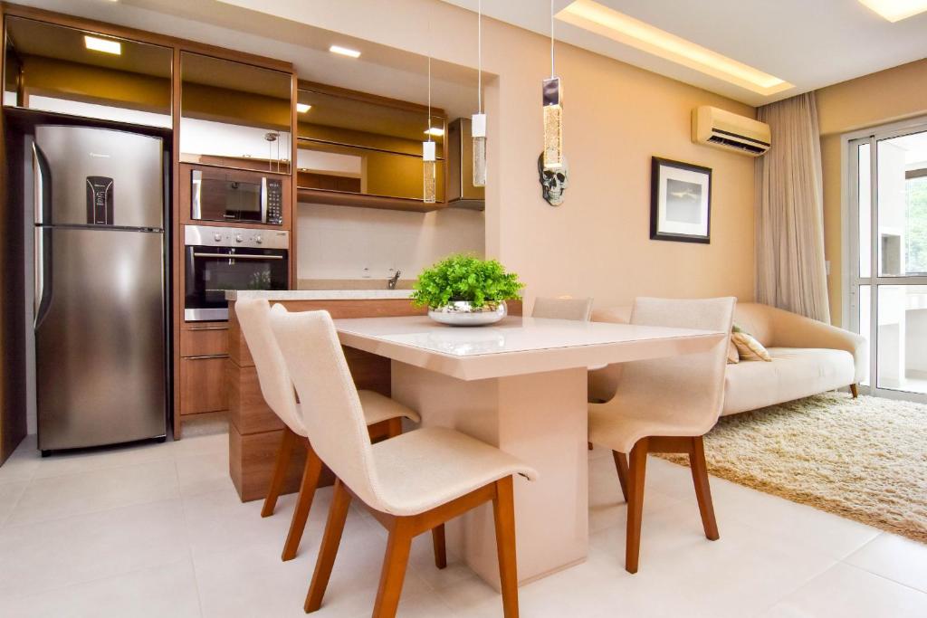 eine Küche und ein Esszimmer mit einem Tisch und Stühlen in der Unterkunft Plaza Saint Tropez, Conforto no Itacorubi P2255 in Florianópolis