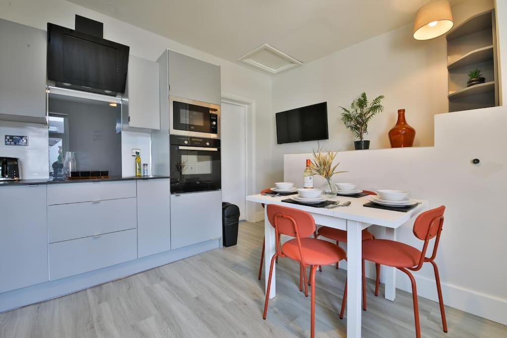 uma cozinha com uma mesa branca e cadeiras vermelhas em StayRight 2 Bedroom City Stays- Vibrant Area near Centre em Cardiff