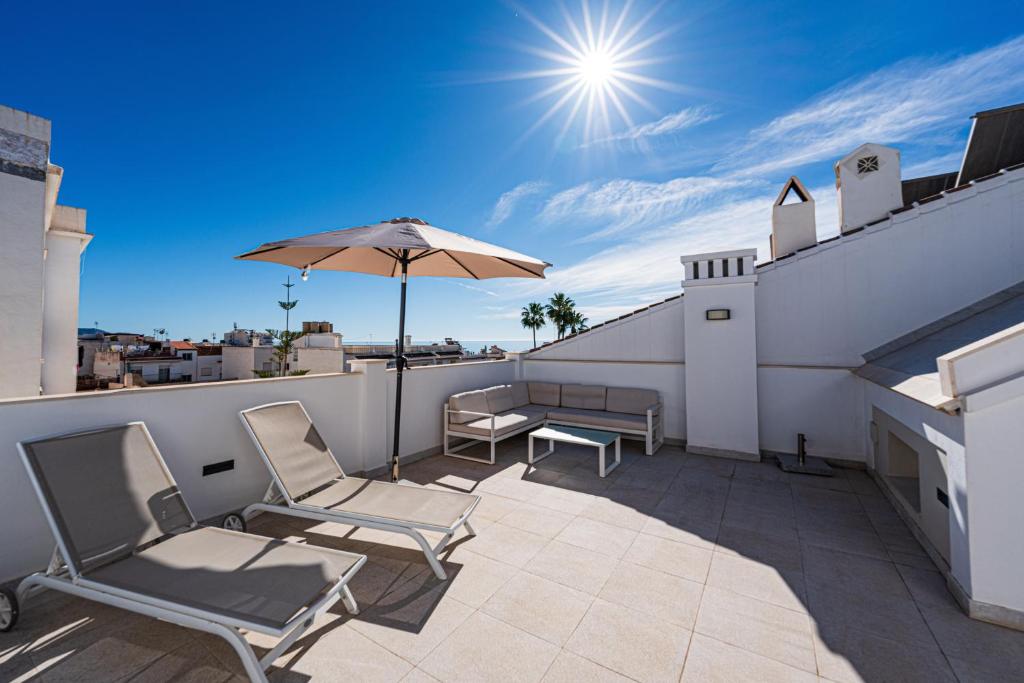 a patio with chairs and an umbrella on a roof at Hostal Boutique Aurora in Nerja
