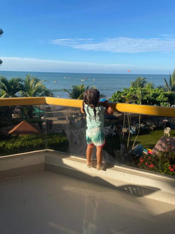 a little girl standing on a balcony looking at the ocean at Departamento en playa almendro in Tonsupa