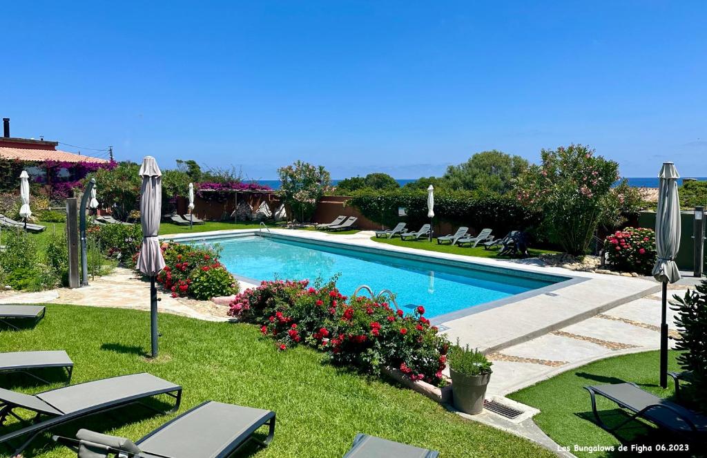 a swimming pool with lawn chairs and umbrellas at Les Bungalows de Figha in Tarcu