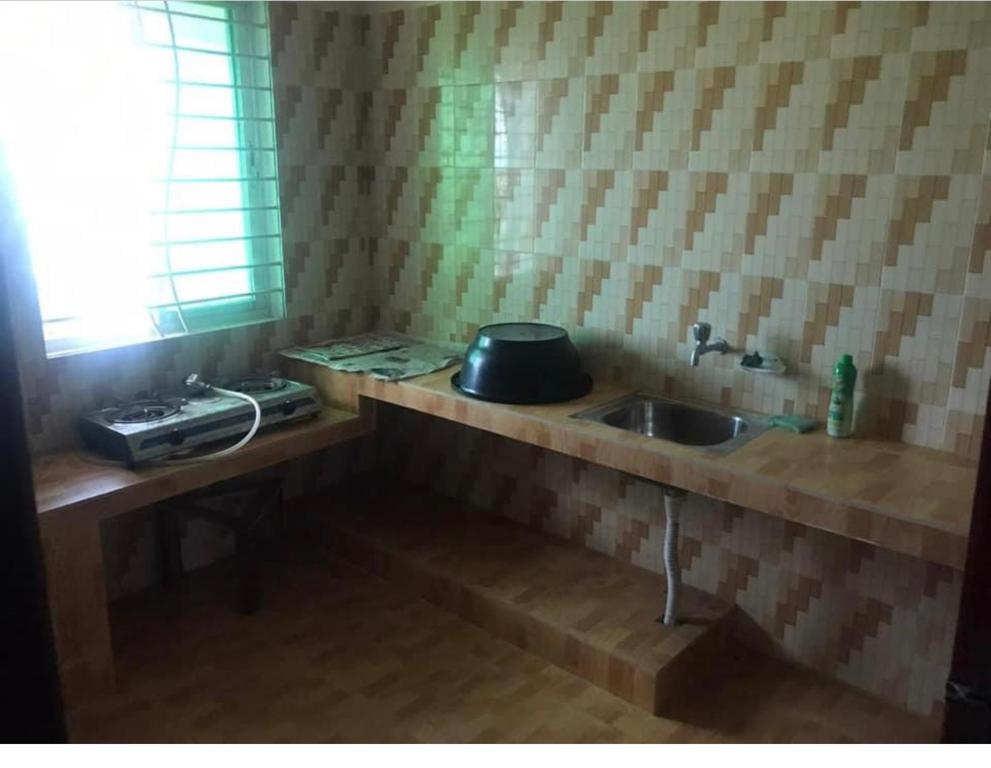 um balcão de cozinha com um lavatório e uma janela em 157 Sorno Shika Ekanto niketon em Sylhet