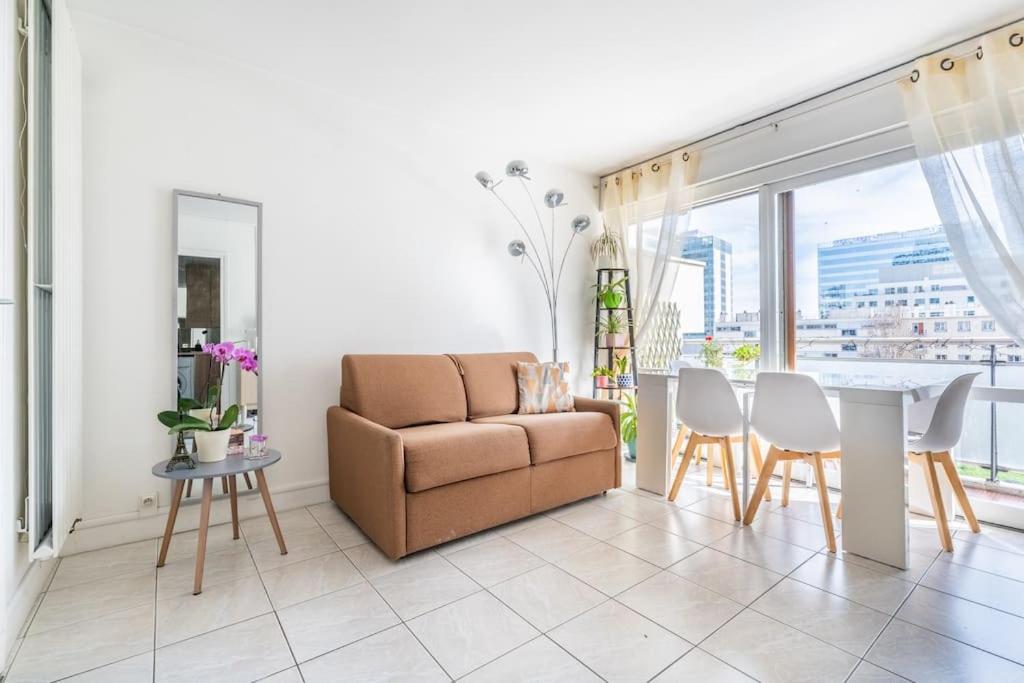 ein Wohnzimmer mit einem Sofa, einem Tisch und Stühlen in der Unterkunft Appartement Lumineux avec Balcon à Courbevoie in Courbevoie