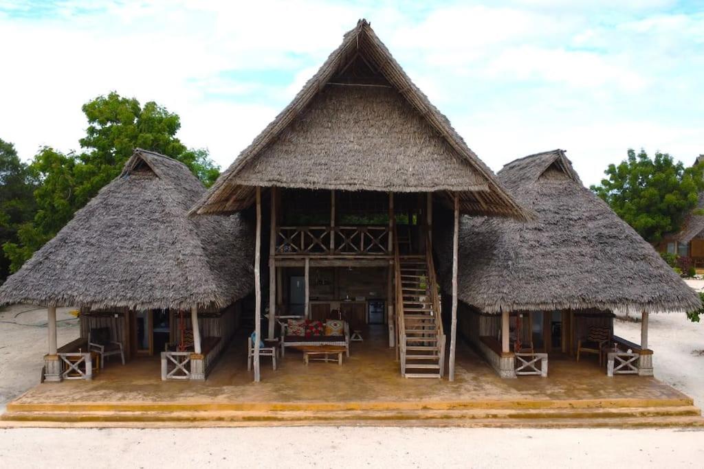 een huis met twee rieten hutten op het strand bij Sunset Getaway- Villa Makuti in Kizimkazi