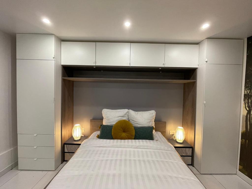 een slaapkamer met een groot wit bed met 2 lampen bij Studio confortable 5’ metro in Vitry-sur-Seine