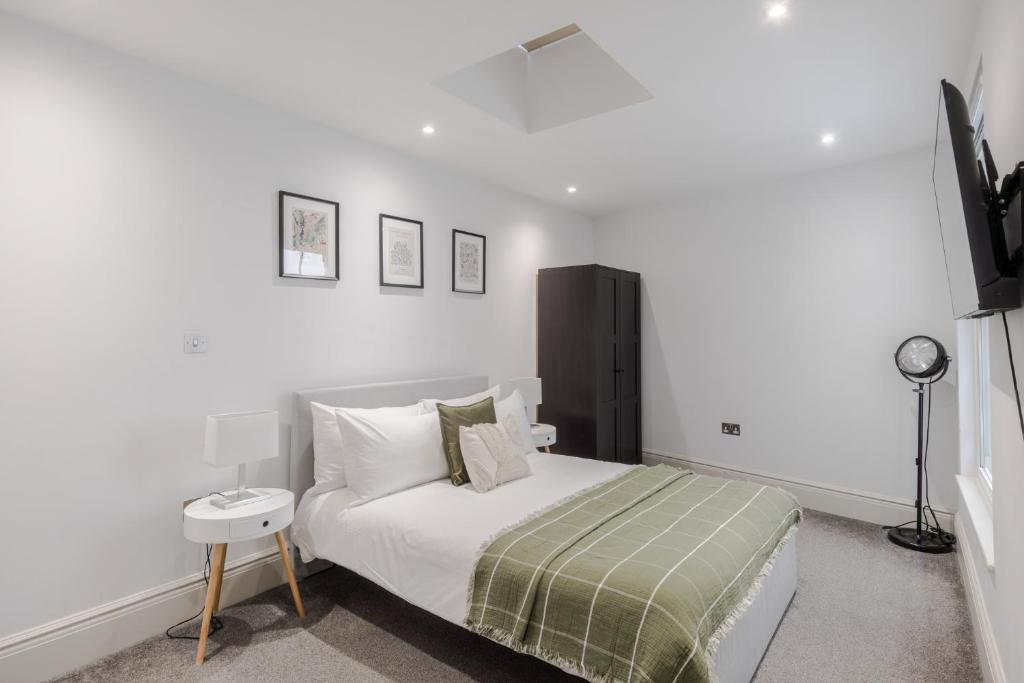 a white bedroom with a bed and a tv at Park view / Baker Street / Marylebone Apartments in London