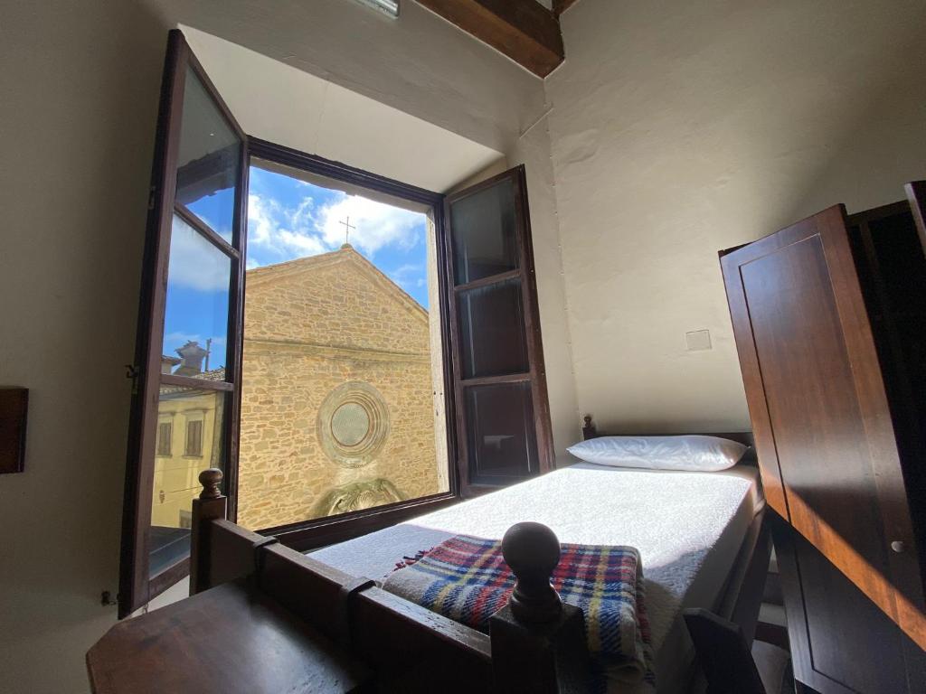 Schlafzimmer mit einem großen Fenster mit Blick auf ein Gebäude in der Unterkunft Ostello San Marco Cortona in Cortona
