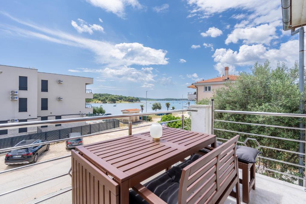 a balcony with a wooden table and a view of the water at 30m zum Meer, Privatparkplatz, Balkon, Netflix in Medulin