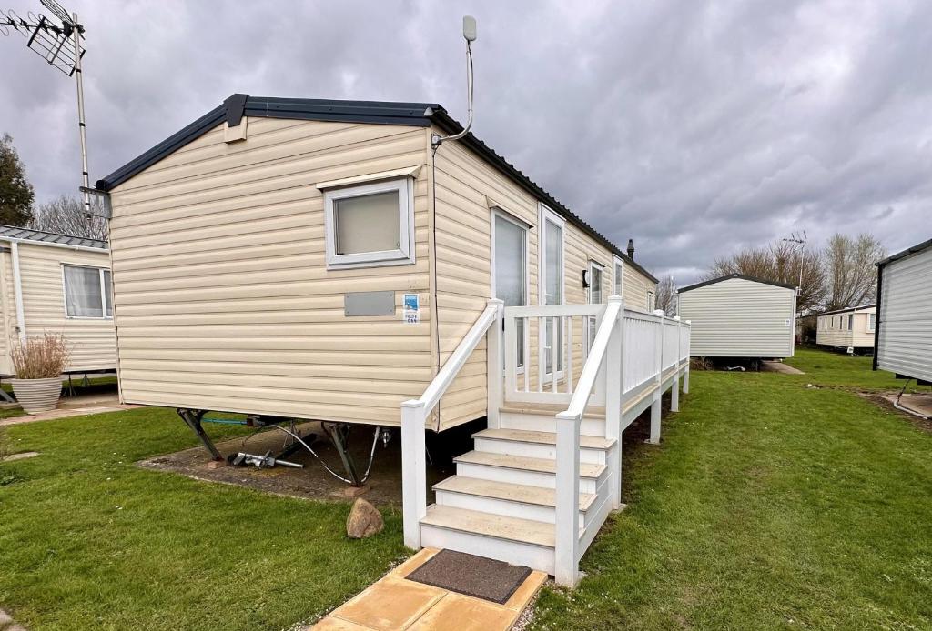 a tiny house with a staircase in a yard at Great Caravan With Wifi And Decking At Dovercourt Holiday Park Ref 44006c in Great Oakley