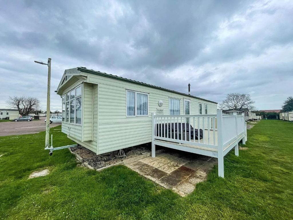 a green house with a porch on a grass field at Lovely Caravan With Decking And Free Wifi At Valley Farm, Essex Ref 46610v in Great Clacton