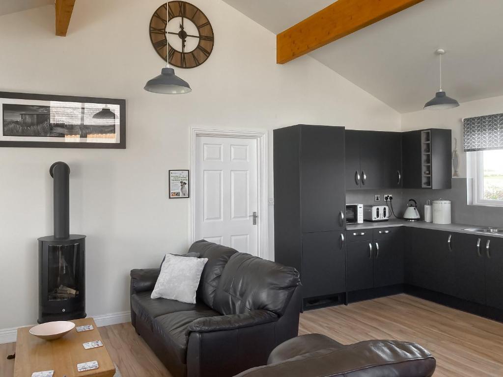 a living room with a couch and a clock on the wall at The Beeches in Warkworth