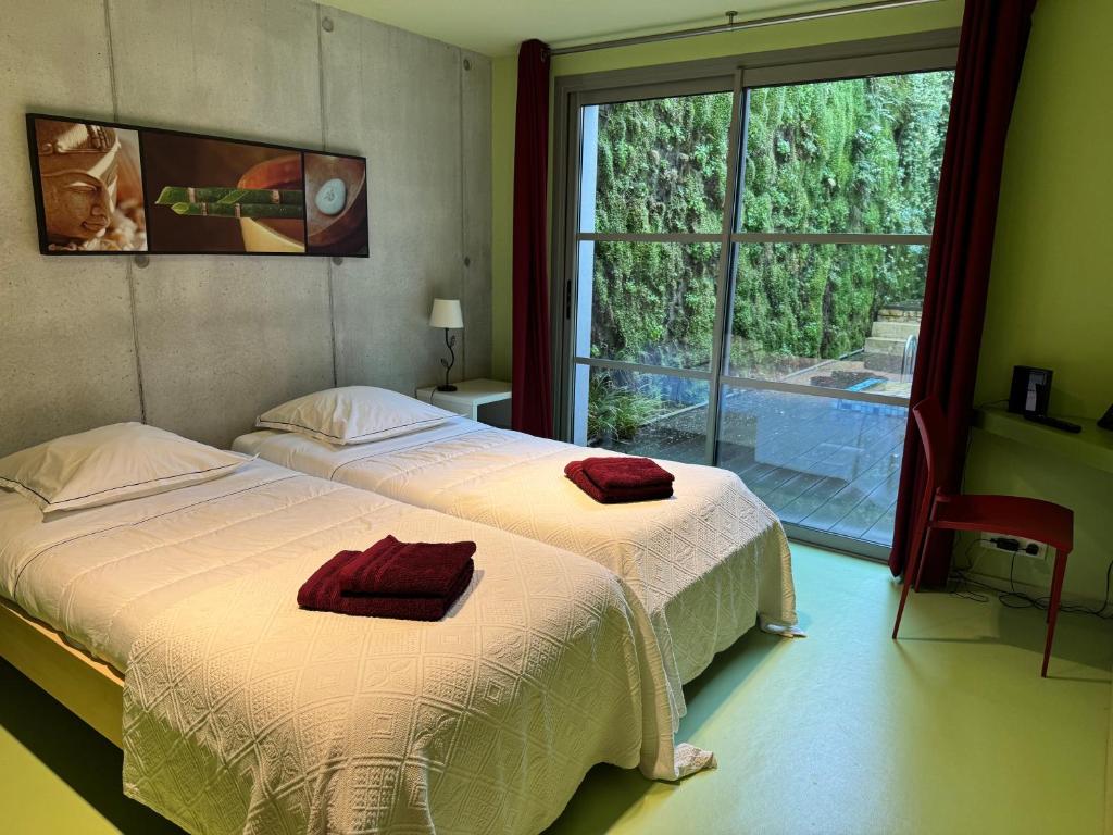two beds in a room with a large window at ღ Villa des Astres 850 m2 - Piscine, Sauna, Hammam, & Salle de Cinéma in La Noue