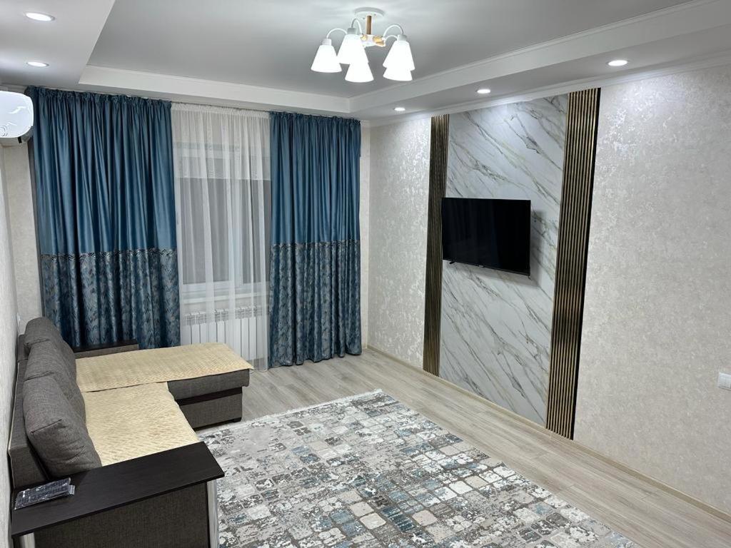 Il comprend un salon doté d'un canapé et d'une télévision à écran plat. dans l'établissement 3х комнатная квартира, à Chimkent