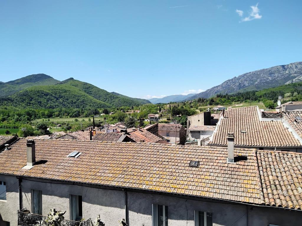 vistas a una ciudad con tejados de baldosa y montañas en Studio cosy duplex dans château médiéval, en Le Poujol-sur-Orb