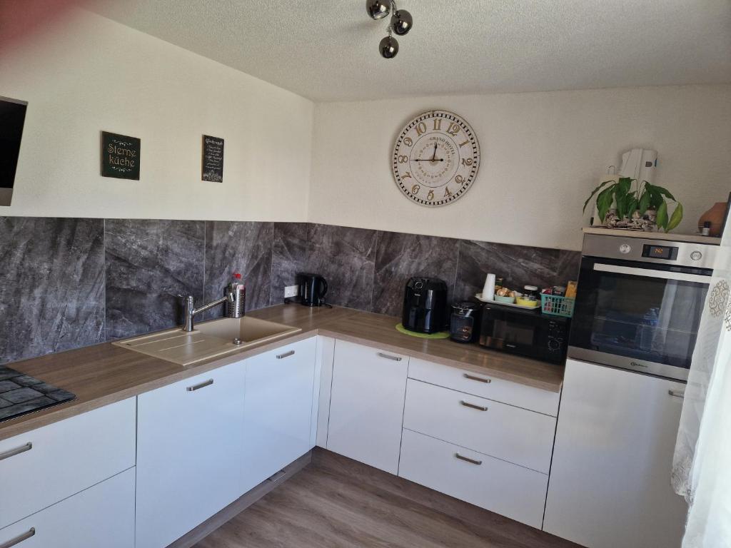 a kitchen with white cabinets and a clock on the wall at Ferienhaus AyNa in Bad Säckingen