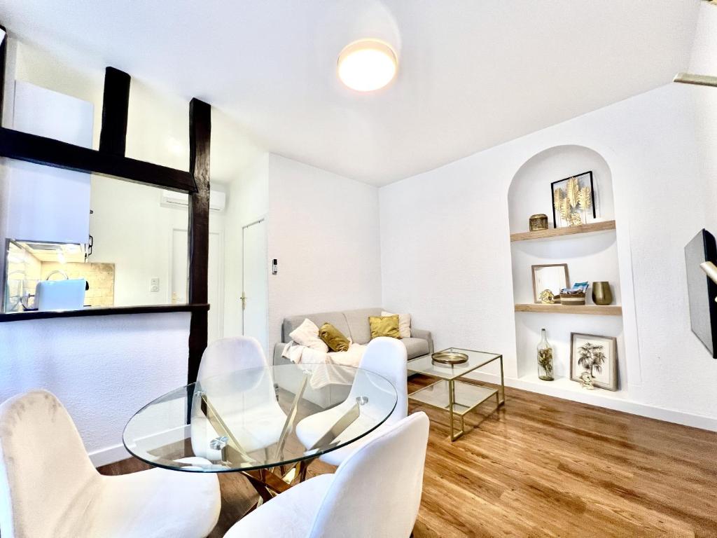 ein Wohnzimmer mit einem Glastisch und weißen Stühlen in der Unterkunft Les Logis d'Esmeralda-Des appartements au charme intemporel in Romorantin