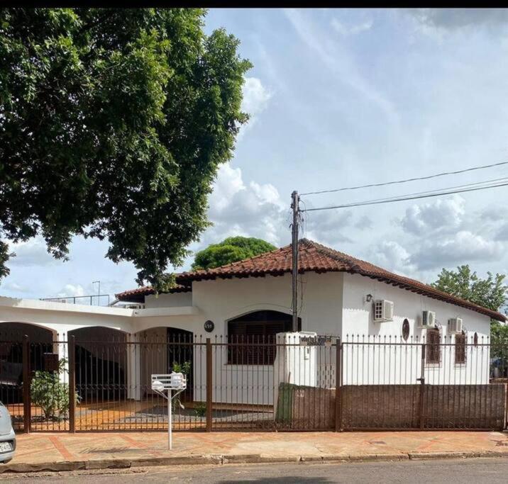 a white house with a fence in front of it at Casa espaçosa centro capital MS in Campo Grande