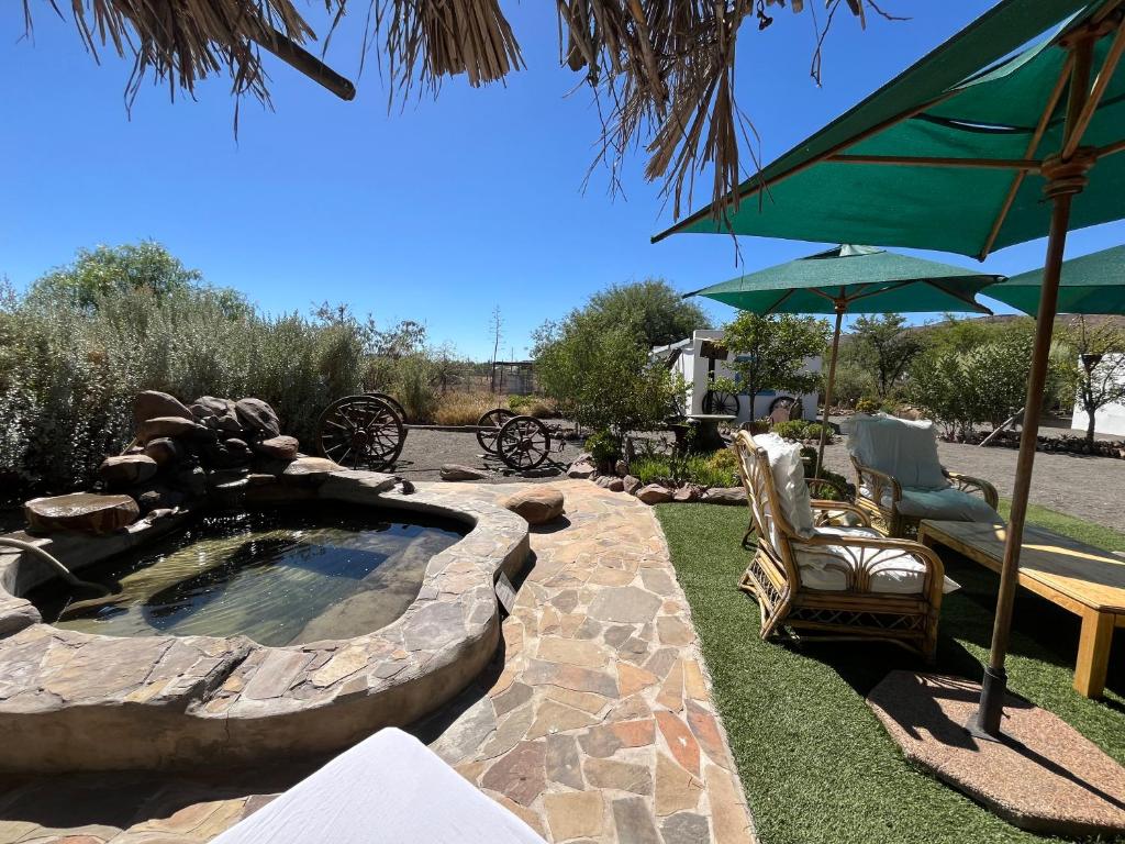 a patio with a hot tub and a chair and an umbrella at Oasis Cottage in Merweville in Merweville