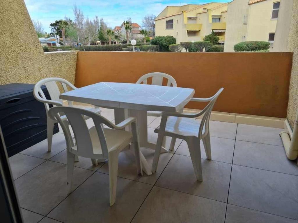 une table et des chaises blanches assises sur un balcon dans l'établissement Appartement 2 pièces 4 pers avec terrasse, parking privé et accès direct plage à Marseillan - FR-1-326-791, à Marseillan