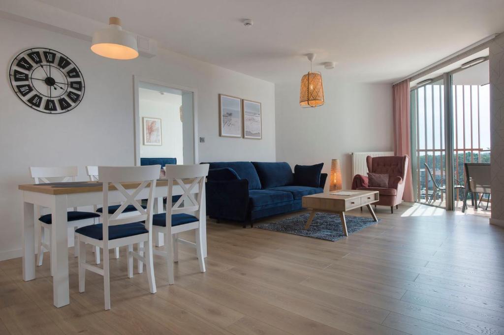 a living room with a blue couch and a table at Apartament Superior PINEA 501 in Pobierowo