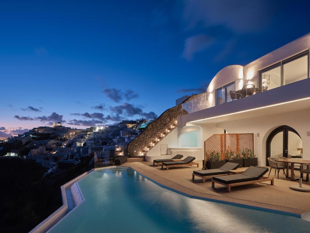 a villa with a swimming pool at night at Olvos Luxury Suites in Oia