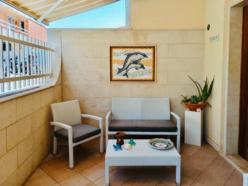 eine Terrasse mit 2 Stühlen, einer Bank und einem Tisch in der Unterkunft Casa Vacanza Mare Blu in Villaggio Azzurro