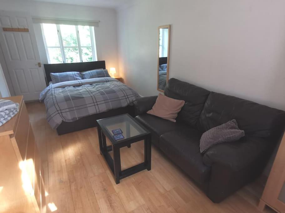 a living room with a couch and a bed at Beautiful Airbnb with Ensuite Rooms in Shenley Church End