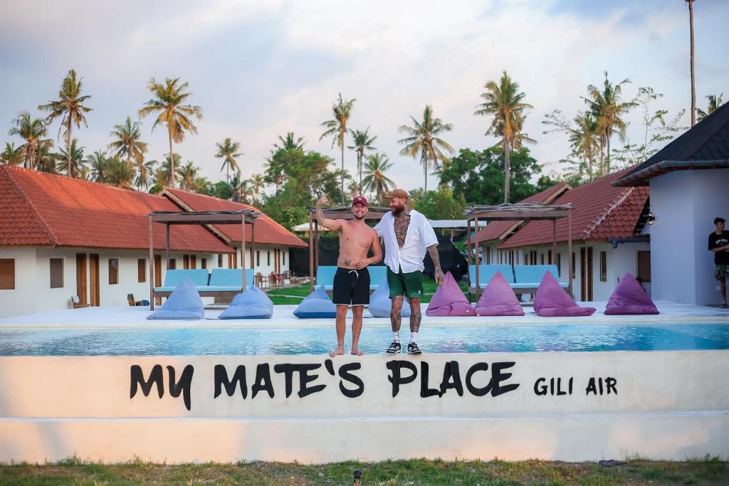 two men standing on the edge of a swimming pool at My Mate's Place Gili Air in Gili Air