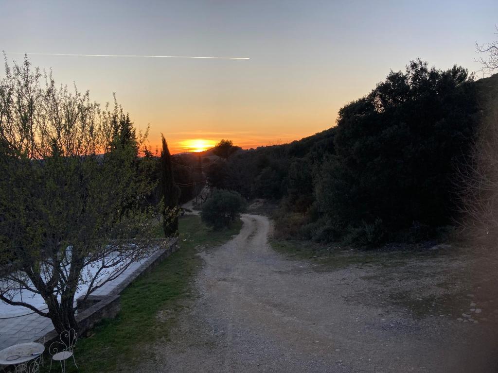 a dirt road with the sunset in the background at Maison au Colorado Provençal in Rustrel