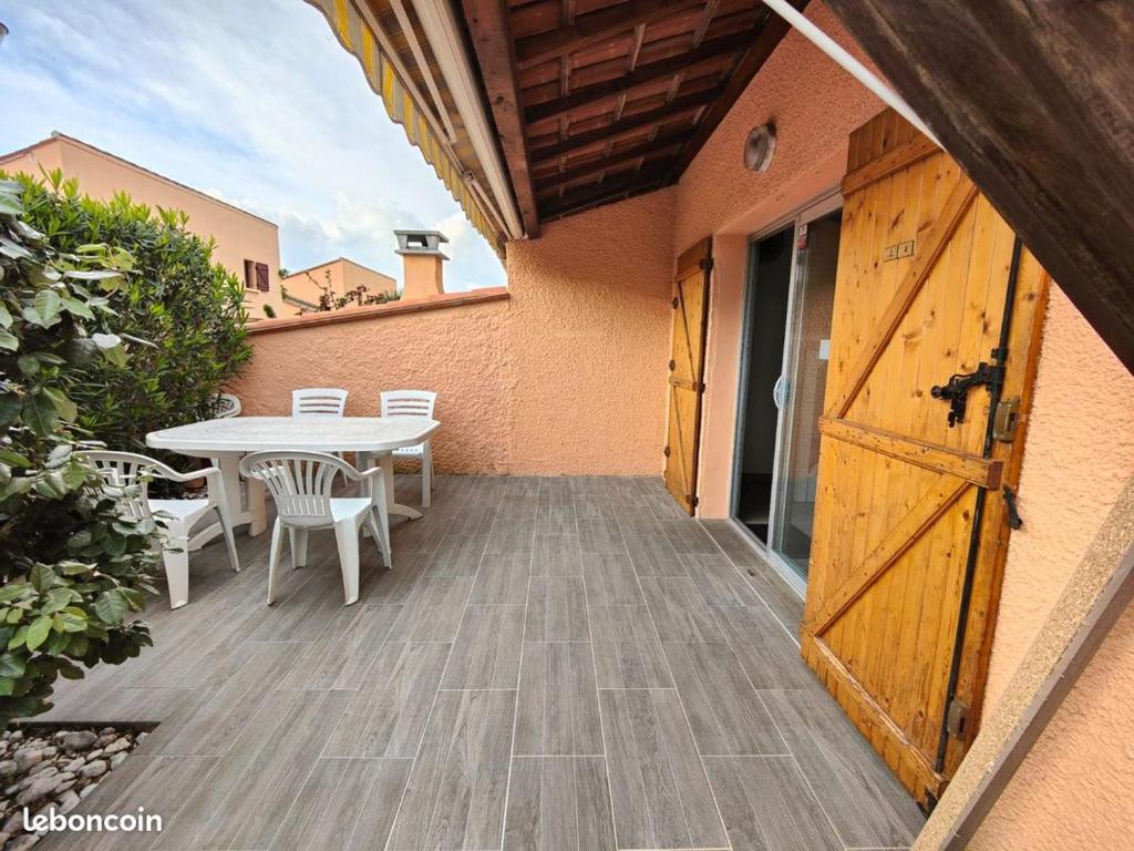 un patio avec une table et une porte en bois dans l'établissement Les Coralines - Jolie villa de vacances - Piscine - Wifi - Clim, à Saint-Cyprien