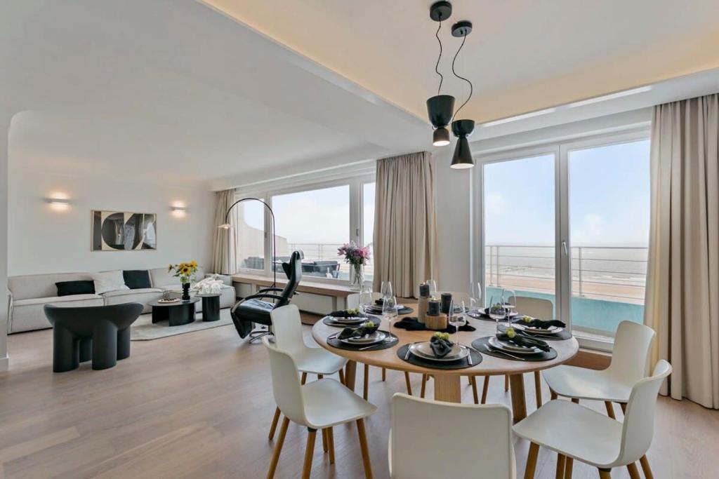 een eetkamer en een woonkamer met een tafel en stoelen bij Stunning fully renovated apartment with panoramic sea-view in 't Zoute with 2 parkings in Knokke-Heist