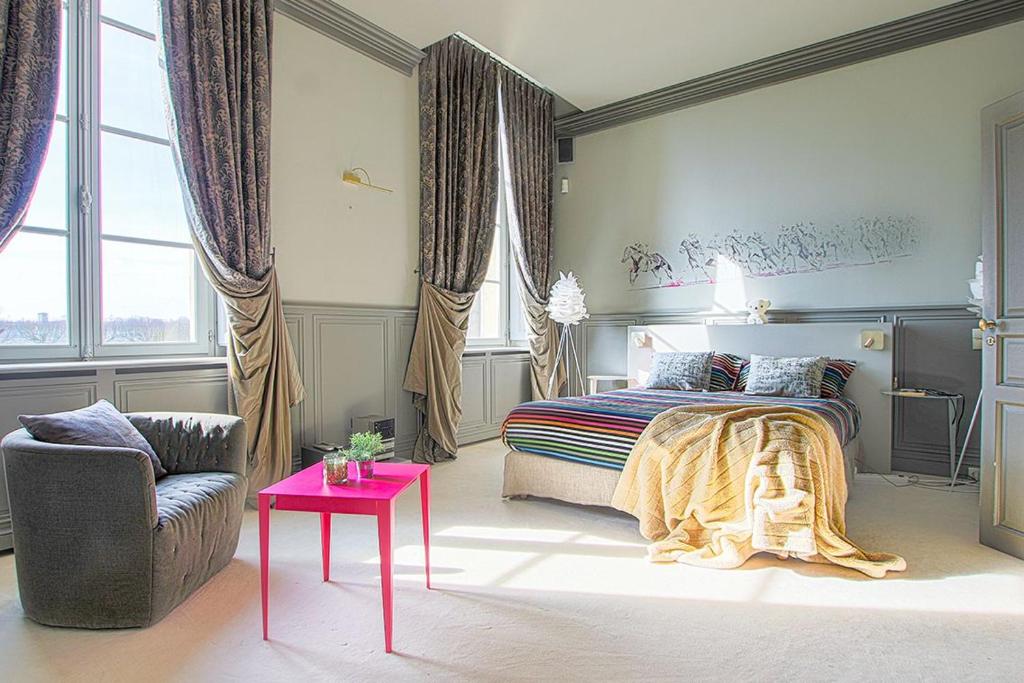 a bedroom with a bed and a chair and a table at Duplex d'exception face Hippodrome avec Jardin in Chantilly