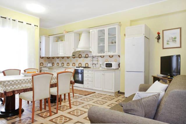 ein Wohnzimmer mit einem Tisch und einer Küche in der Unterkunft Casa Vacanze Rosy in Giardini-Naxos