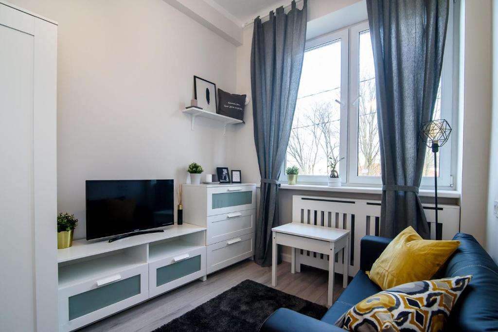 a living room with a blue couch and a tv at Cozy Loft / Near Gates of Dawn / Free Netflix in Vilnius