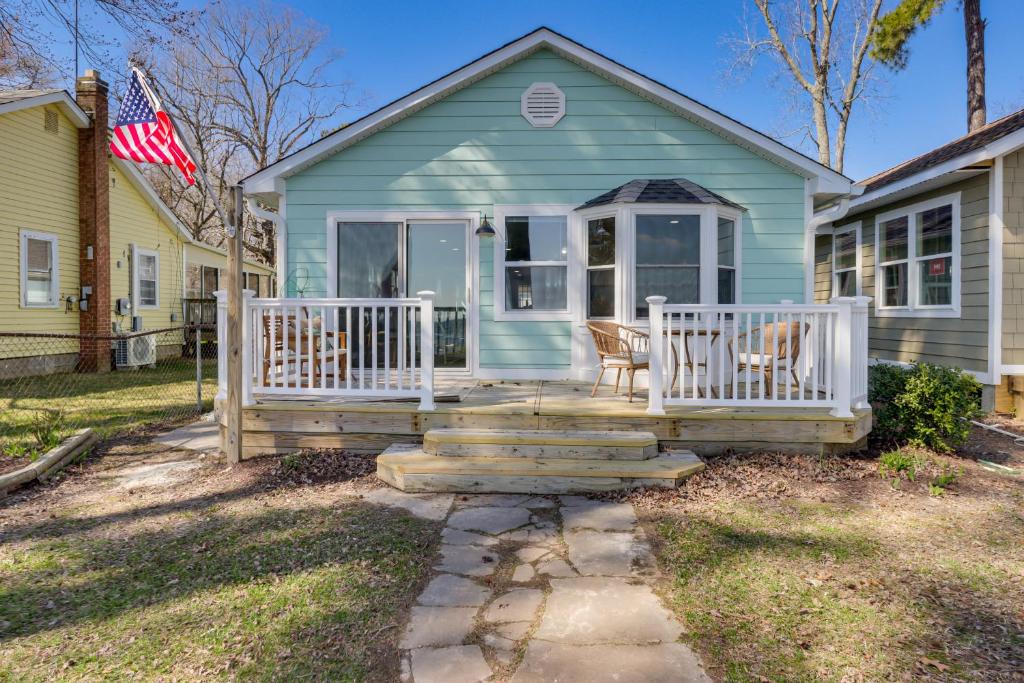 a blue house with a porch and a flag at Bayfront Maryland Retreat with Deck, Near Beaches! in North Beach