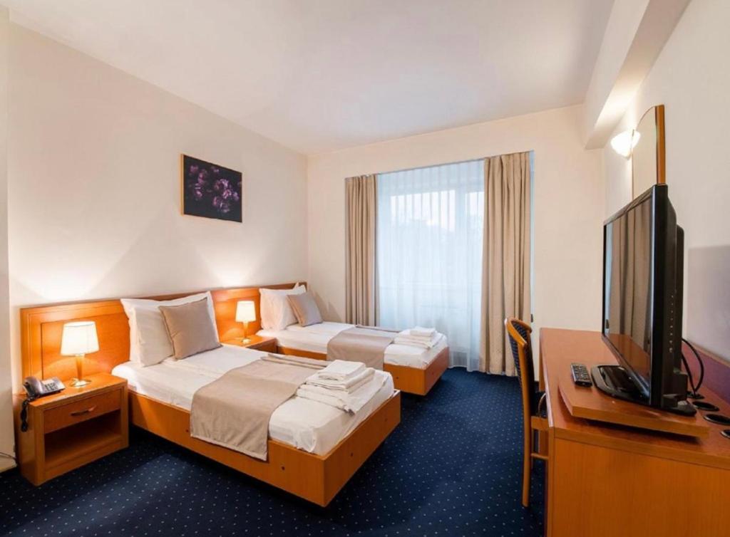 a hotel room with two beds and a flat screen tv at Hotel Pension Matteo in Augsburg