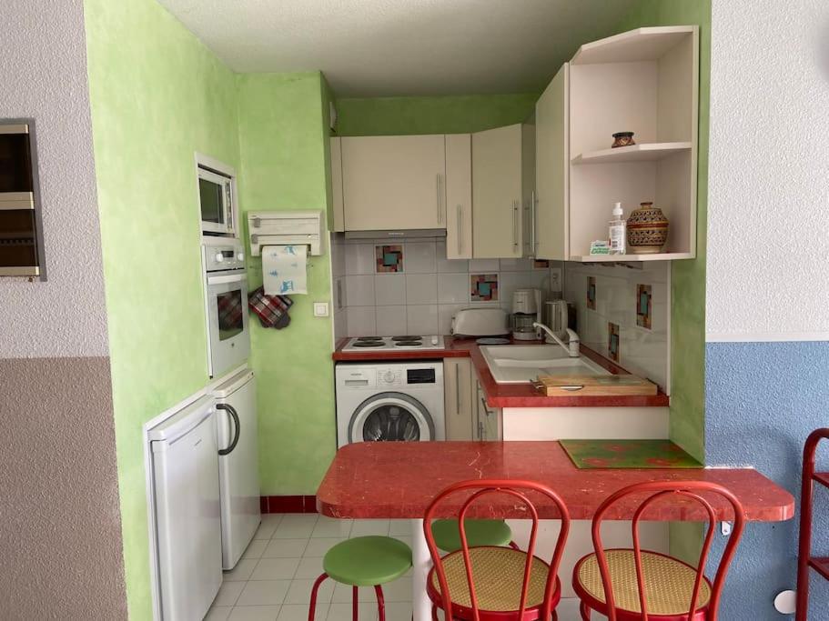 - une cuisine avec des murs verts et blancs, une table et des chaises dans l'établissement P2 La Grande Motte, à La Grande Motte