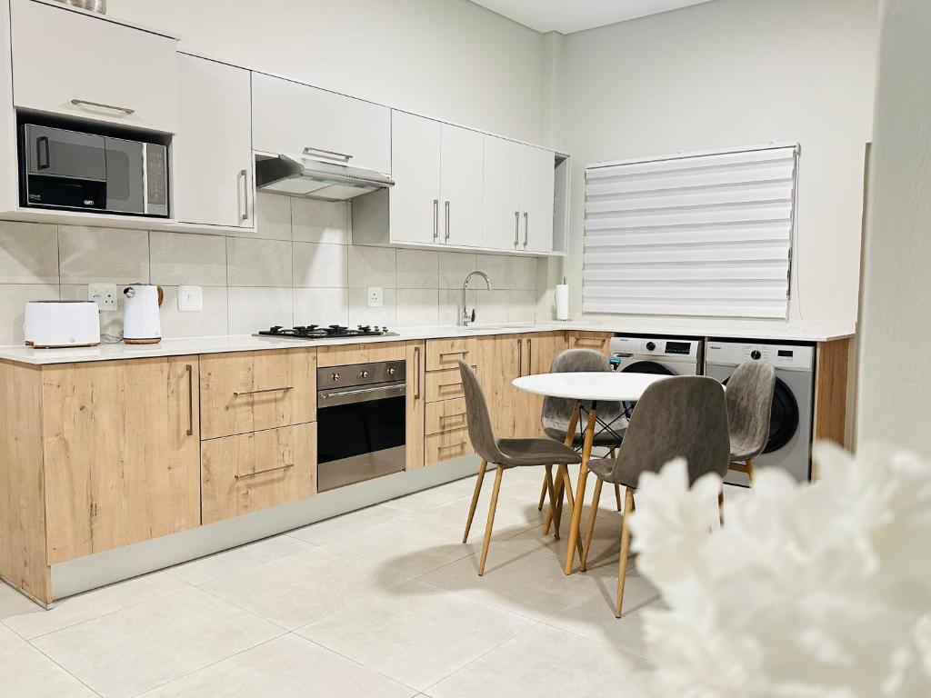 a kitchen with white cabinets and a table and chairs at Shamah in Pretoria