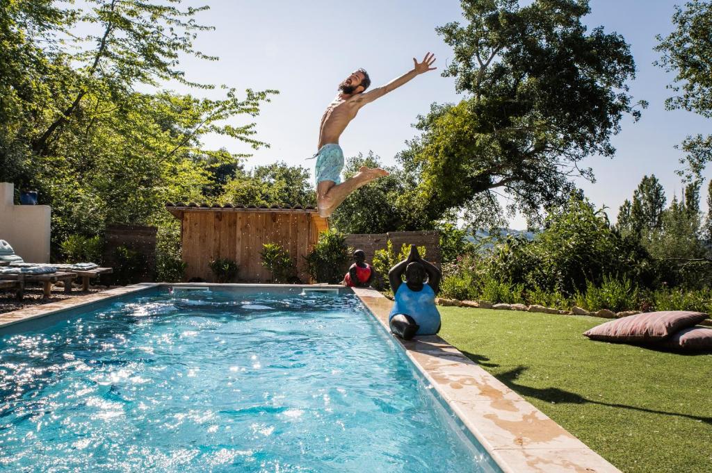 un hombre saltando al aire sobre una piscina en Bulles d'Olive - Zome Céleste en Nyons