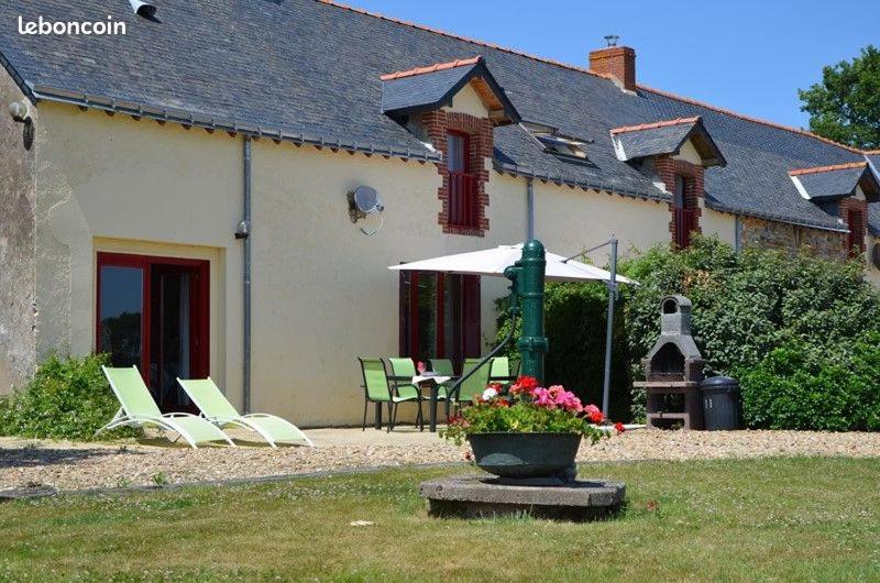 une maison avec une table, des chaises et un parasol dans l'établissement Domaine Lauxley du Loc'h, à Avessac