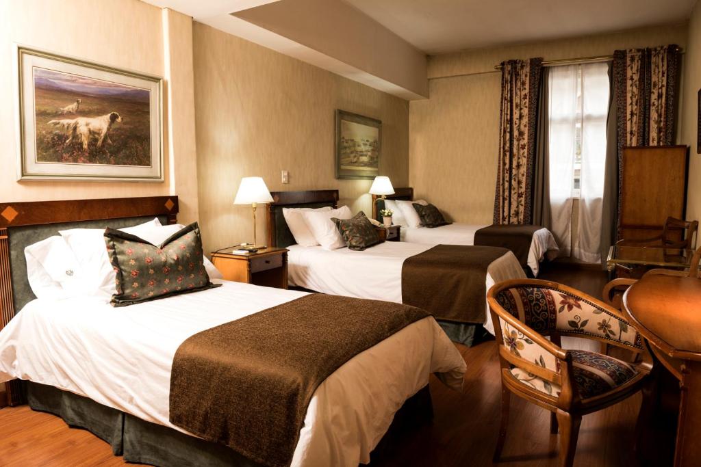 a hotel room with two beds and a chair at Mayflower Suites in Buenos Aires