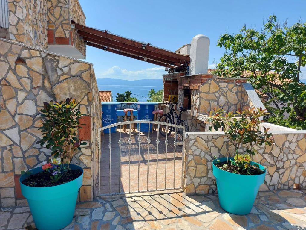a gate with two potted plants on a stone wall at Apartmani Omišalj in Omišalj