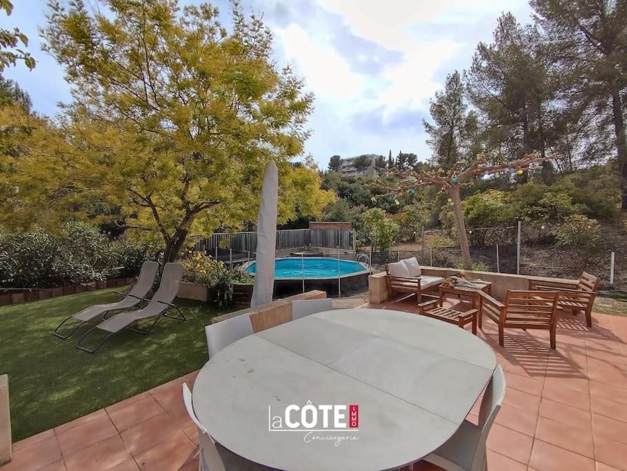 a patio with a table and chairs and a pool at Villa les Cigales - 8 couchages in Carry-le-Rouet