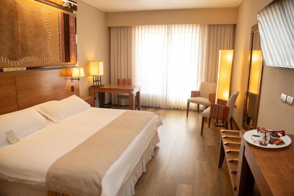 a hotel room with a large bed and a table at Alejandro 1º Hotel in Salta